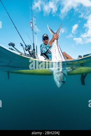 Split shot of man in a kayak catching a fish Stock Photo