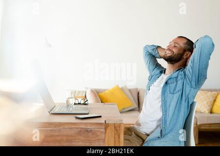 Young man at home working on his laptop in home office having a break Stock Photo