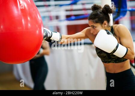 Female boxer training at punch bag in gym Stock Photo