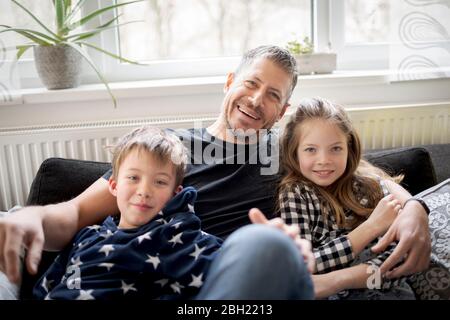 Portrait of happy father with kids relaxing on couch at home Stock Photo