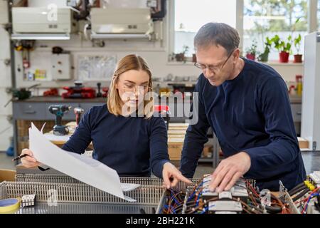 Two electricians working on circuitry in workshop Stock Photo