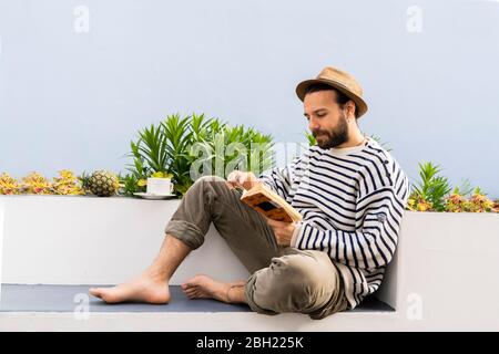 Man sitting on balcony reading a book Stock Photo
