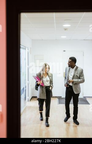 Colleagues walking and talking in office Stock Photo