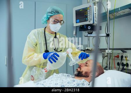 Doctor with bag valve mask caring for patient in emergency care unit of a hospital Stock Photo