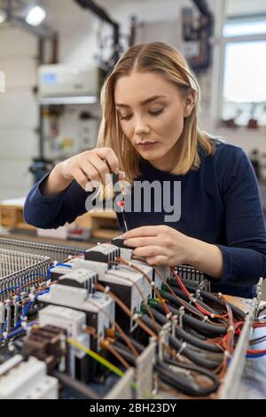 Female electrician working on circuitry in workshop Stock Photo