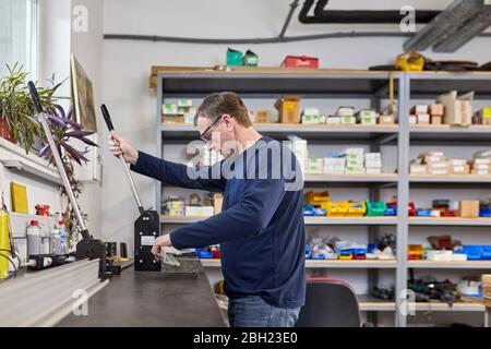 Man using punching machine in workshop Stock Photo