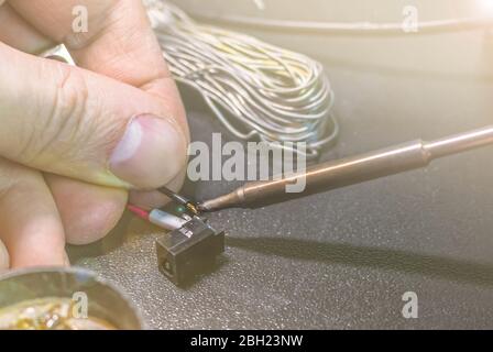 technical master soldering parts with a soldering iron. resin, the smoke, the battery, wires. technical support, repair Stock Photo