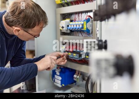Electrician working on circuitry in workshop Stock Photo