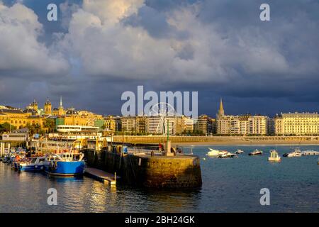 Spain, Gipuzkoa, San Sebastian, Storm clouds over harbor of coastal town
