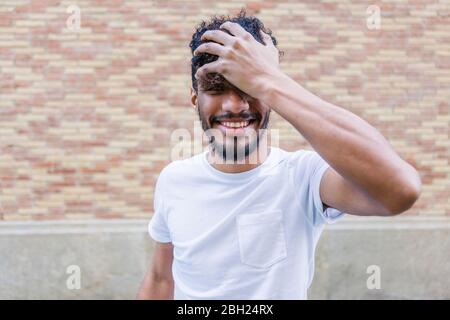 Portrait of laughing young man with hand in his hair Stock Photo