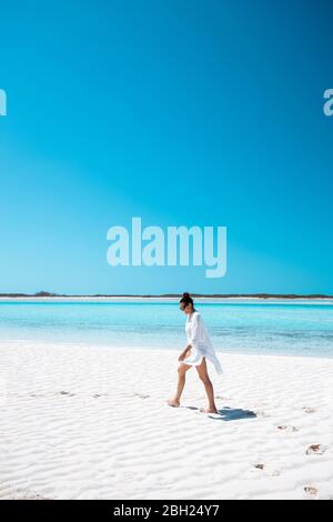 Woman walking on white sand bank in the sea, Bahamas, Carribean Stock Photo