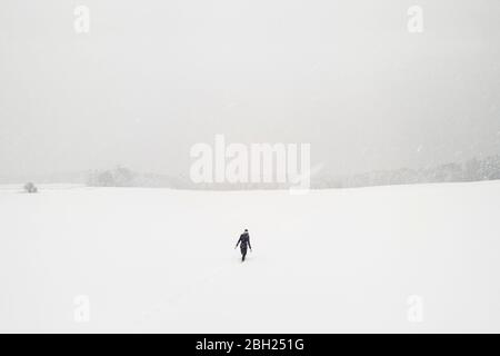 Woman walking alone in snow-covered landscape
