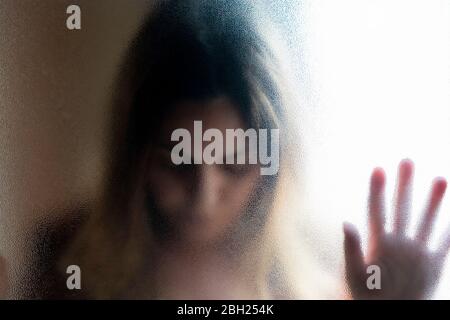 Portrait of mature woman with eyes closed behind glass pane Stock Photo
