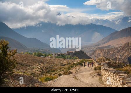 Himalayan landscape, view of the village of Jharkot surrounded by mountain ranges. Nepalese local women are walking along road to village. Lower Musta Stock Photo