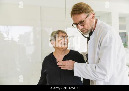 Doctor listening to heartbeat of senior patient Stock Photo