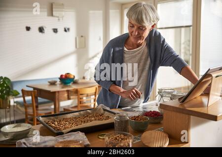 Senior woman preparing granola in kitchen