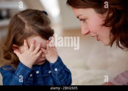 Young mother watching her little daughter covering eyes with her hands Stock Photo