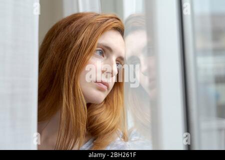 Portrait of serious young woman looking out of window Stock Photo