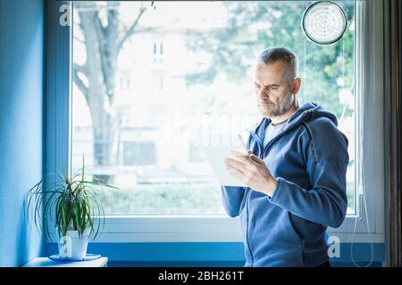 Man using digital tablet near window at home Stock Photo