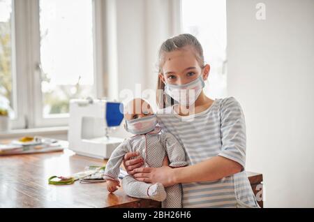 Little girl and her doll, wearing self.made face masks Stock Photo