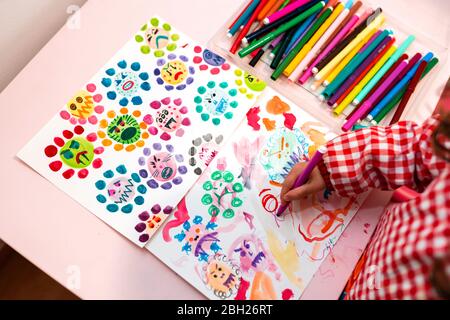 Little girl drawing  ugly viruses with color markers at home Stock Photo