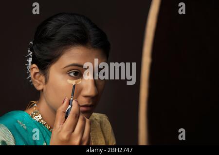 Kathak dancer applying makeup on her face. Stock Photo