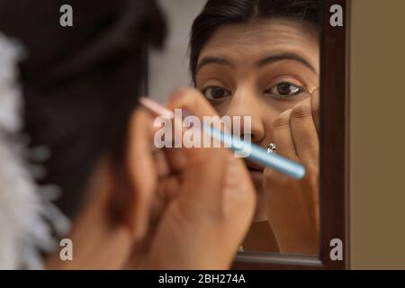 Kathak dancer applying makeup on her face. Stock Photo
