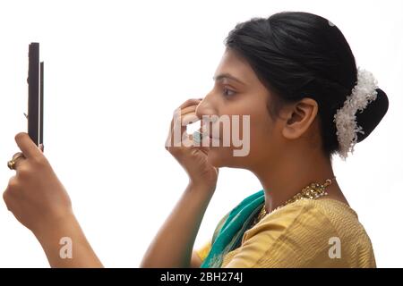 Kathak dancer applying makeup on her face. Stock Photo