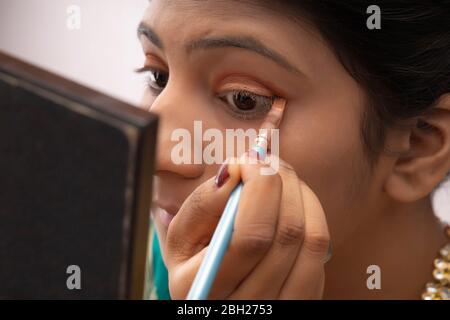 Kathak dancer applying makeup on her face. Stock Photo