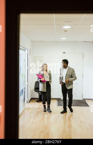 Colleagues walking and talking in office Stock Photo
