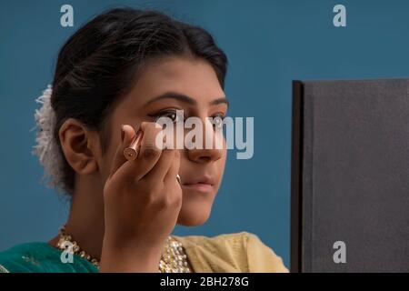 Kathak dancer applying eyeliner on her eyes. Stock Photo