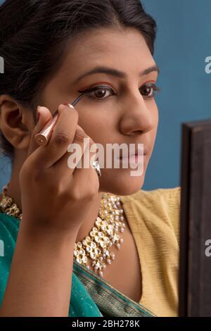 Kathak dancer applying eyeliner on her eyes. Stock Photo