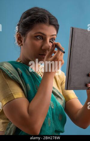 Kathak dancer applying eyeliner on her eyes. Stock Photo