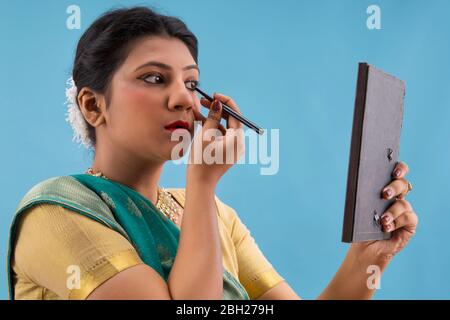 Kathak dancer applying eyeliner on her eyes. Stock Photo