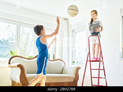 Boy and girl playing basketball in living room Stock Photo