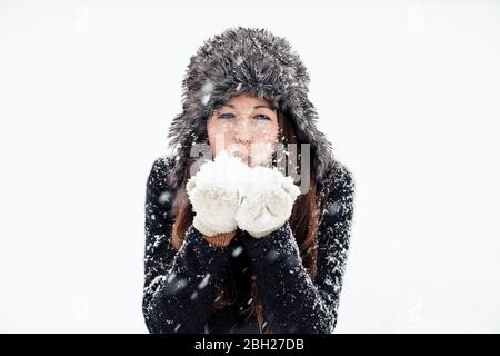 Portrait of young woman blowing snow Stock Photo