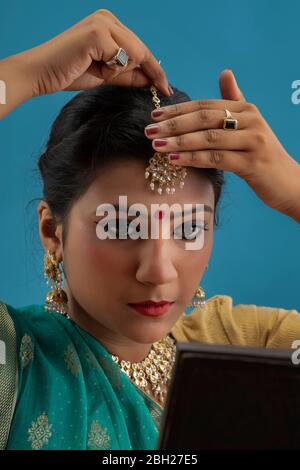 Kathak dancer looking in the mirror putting mangtika on her head. Stock Photo