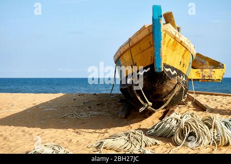 Ghana, Keta, Old fishing boat left on sandy coastal beach Stock Photo
