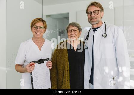 Portrait of doctor, assistant and senior patient in medical practice Stock Photo