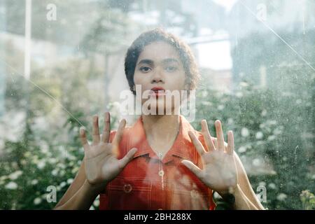 Portrait of young woman behind glass pane Stock Photo