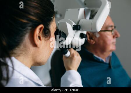 ENT physician examining ear of a senior man Stock Photo