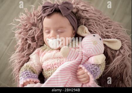 Portrait of sleeping baby girl with hair-band, soft toy and pacifier Stock Photo