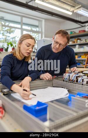 Two electricians working on circuitry in workshop Stock Photo