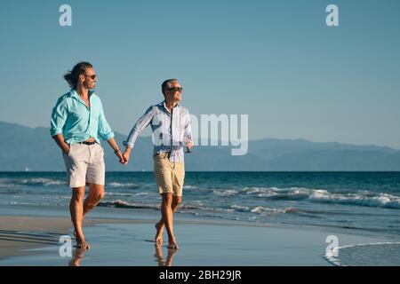 Male gay couple enjoying walk at a beach in Mexico Stock Photo