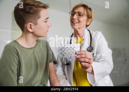 Doctor explaining medication to teenage boy in medical practice Stock Photo