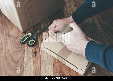 close-up of person sealing up shipping box with parcel tape, pruchase return and return of goods concept Stock Photo