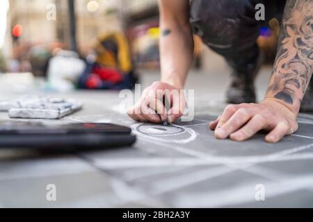 Street art, pavement artist drawing an eye on pavement and using smartphone Stock Photo