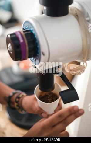 Close-up of woman pouring coffee into cup from a machine Stock Photo