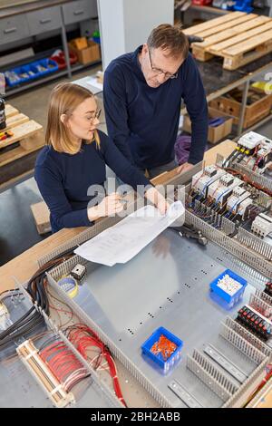 Two electricians working on circuitry in workshop Stock Photo
