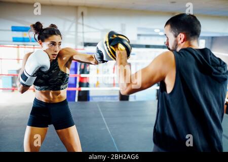 Female boxer sparring with her coach in gym Stock Photo